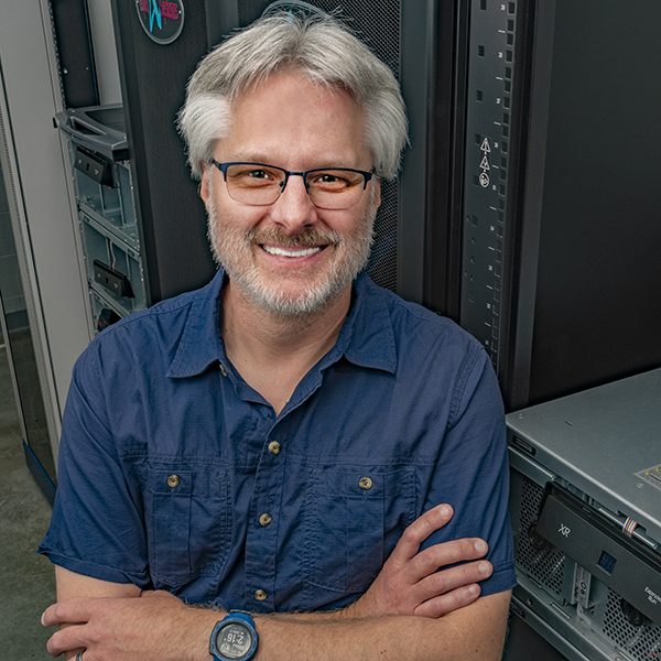 Brian Thomas stands next to a computer server