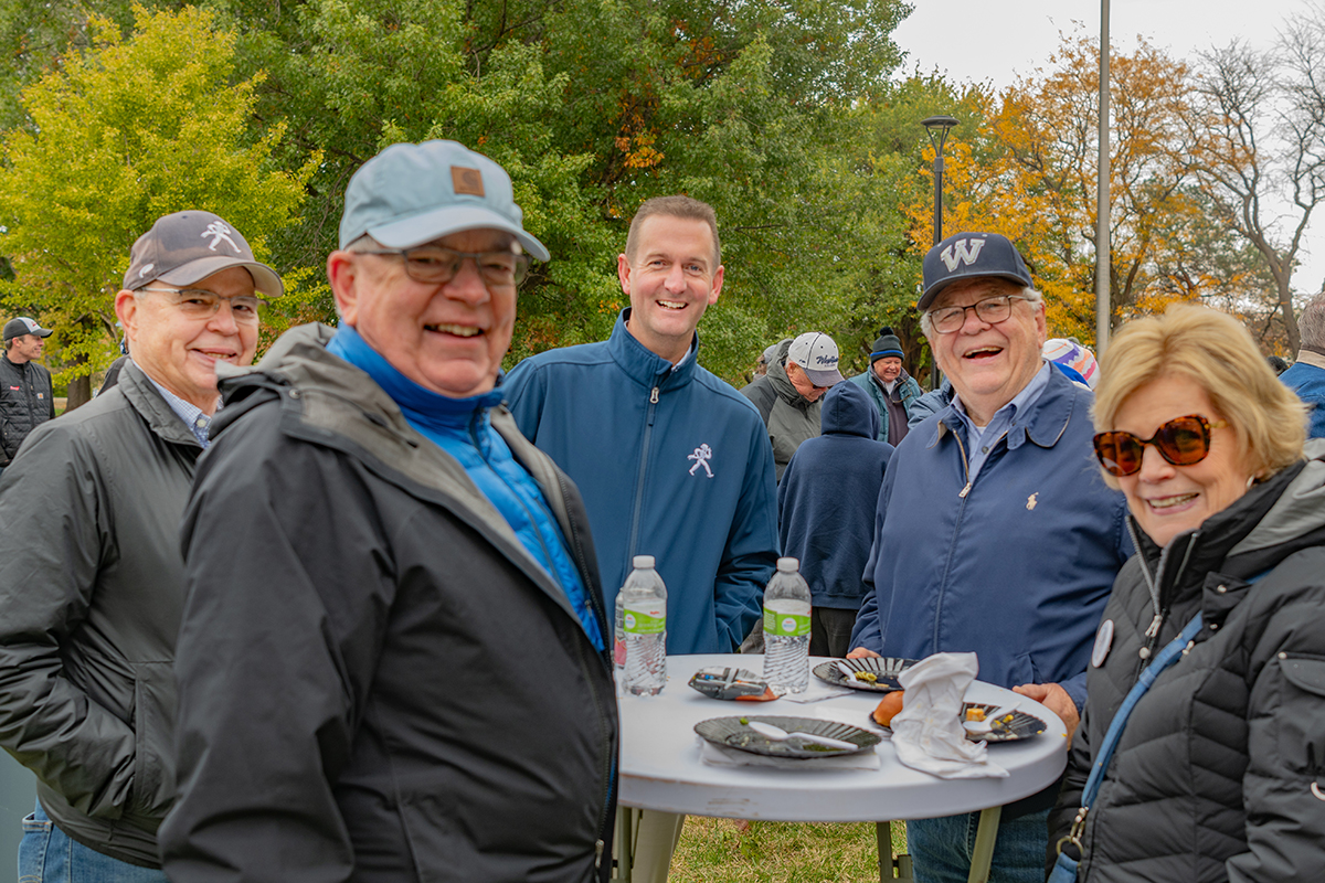 People gathered and posing during an alumni football tailgate
