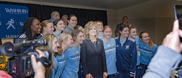 President JuliAnn Mazachek posing with the Washburn women's basketball team