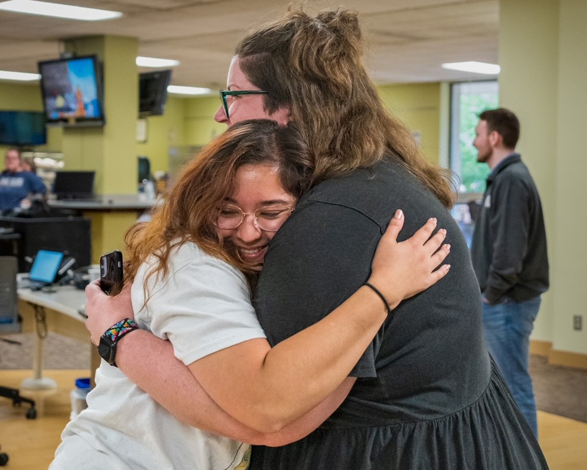 A student and library worker hugging
