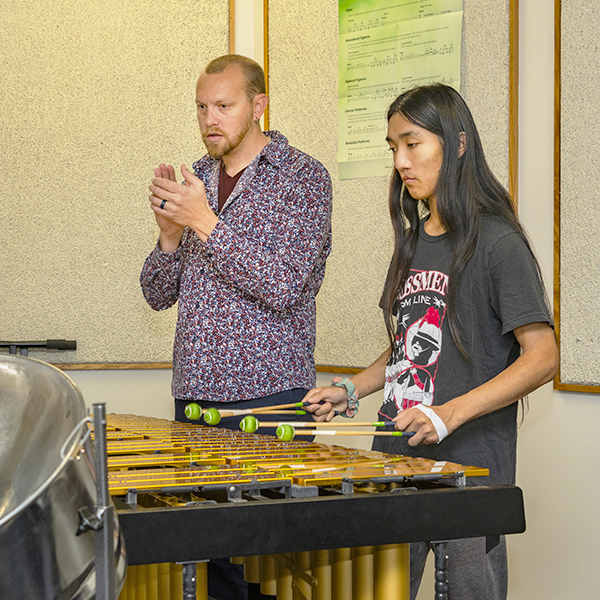 Von Hansen claps to the rhythm as a student plays percussion