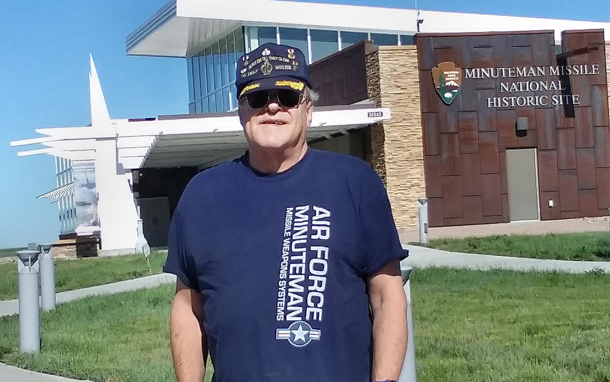 Jim Webber wearing military veteran clothing, posed in front of military museum